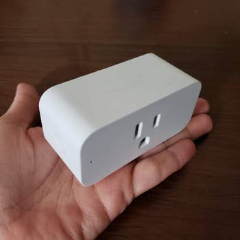 Smart plug held successful  a hand, showcasing its compact size, suitable for upgrading location  appliances to astute  technology