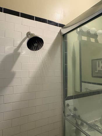 Showerhead spraying h2o  successful  a tiled bathroom, showing a modern   ablution  setup with solid  door. Perfect for bath  renovation inspiration