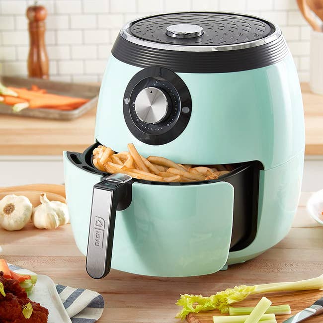 french fries inside the basket of a light blue air fryer