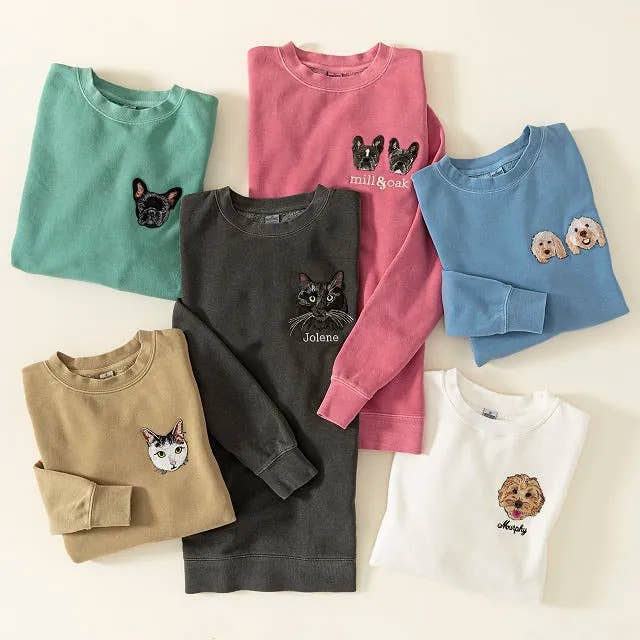 Sweaters in blue, coral, white, nude, black and sage green that all have pets embroidered on the upper left chest 
