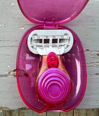 Gillette women’s razor in a pink and red plastic case on a wooden surface