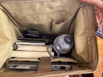Inside a spacious tote container  showing a laptop, notebooks, a h2o  bottle, and a wallet, organized for casual  access