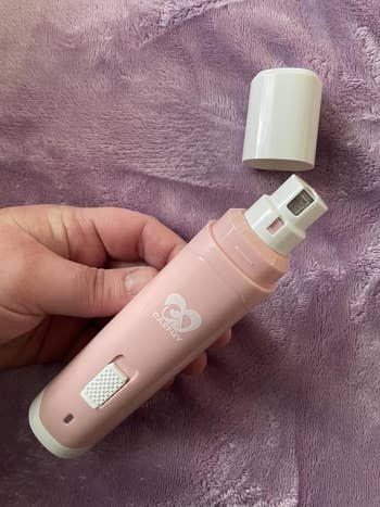 Hand holding a portable electrical favored nail grinder with a information guard. The instrumentality is compact and designed for grooming pets safely astatine home