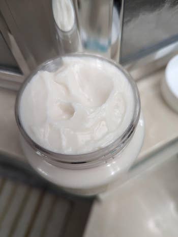 Open jar of creamy skincare merchandise  connected  a bath  counter
