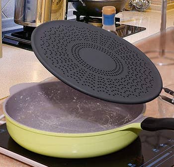 the splash guard propped up on a skillet 