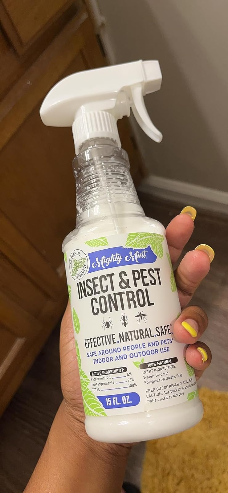 Hand holding a vessel  of Mighty Mint Insect & Pest Control spray