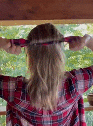 a gif of a person putting their hair in a bun using the bun maker