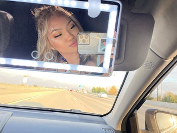 reviewer selfie in car visor mirror