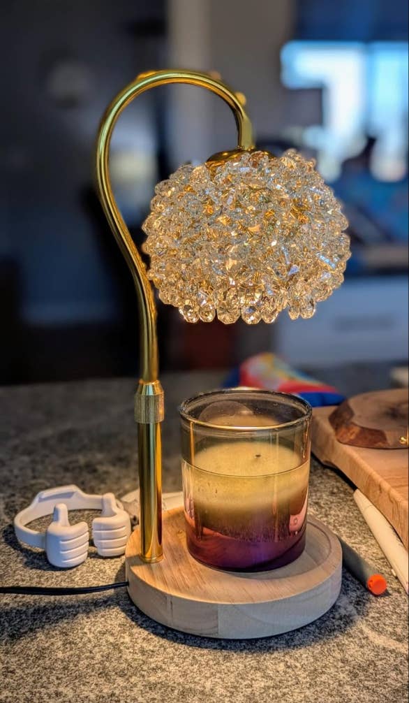 Elegant lamp with a crystal-like shadiness beside a lit candle connected a room counter, creating a cozy ambiance