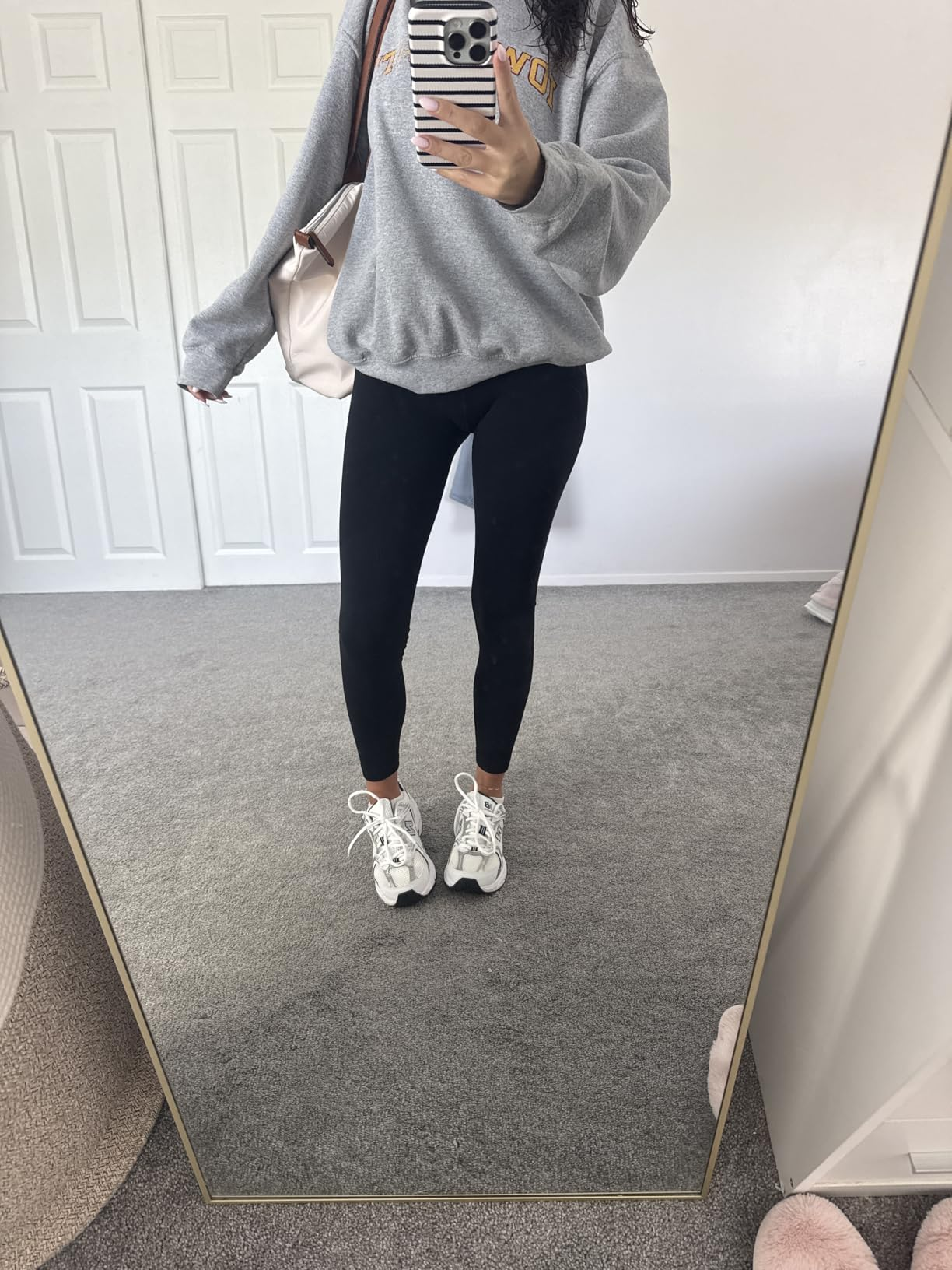 Person successful  a casual outfit with a sweatshirt, leggings, and sneakers takes a reflector  selfie, showcasing a casual athleisure look