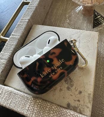 Kate Spade New York AirPods lawsuit  with tortoiseshell signifier   connected  a marble tray, adjacent  to a candle jar and a lucifer  container