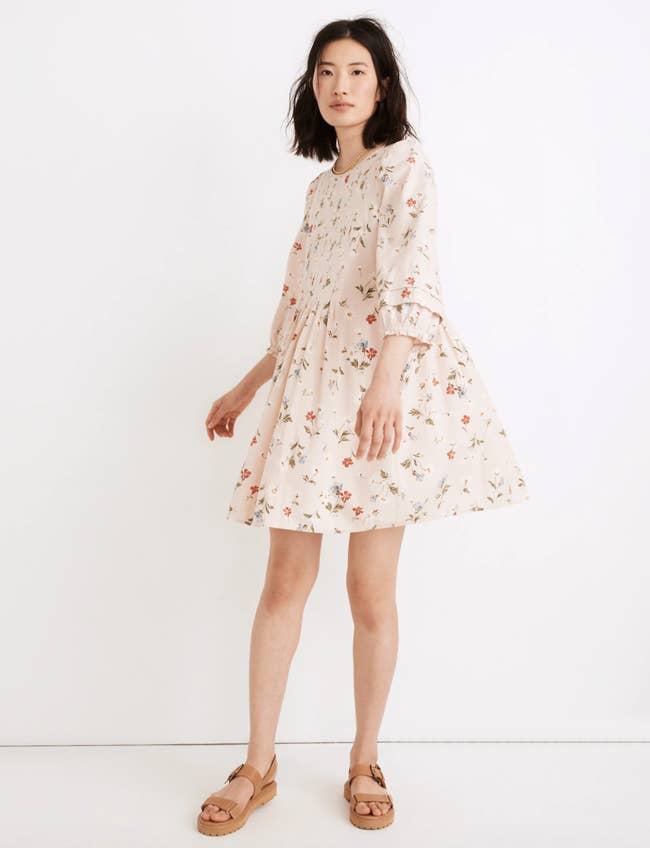 a model in a pale pink dress with puffy quarter sleeves and a floral print