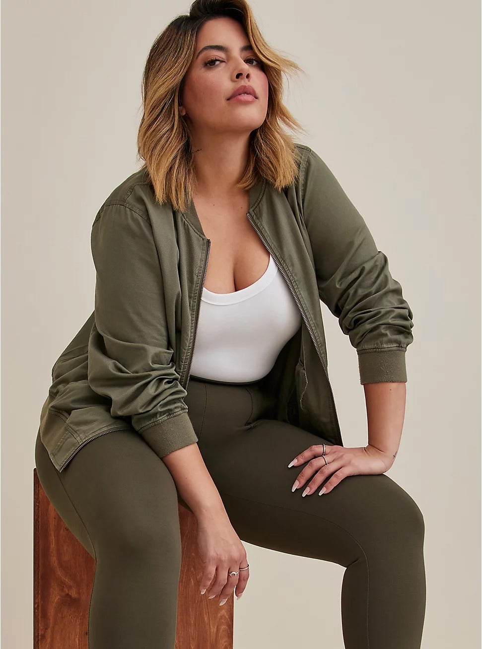 model sitting down, wearing hunter green twill bomber jacket