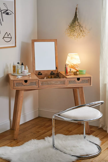brown vanity with mirror and cane drawers in the corner of a bedroom