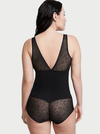 model showing the backside of the black bodysuit, with sheer lace at the straps and bottom area