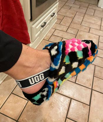 Person's feet wearing colorful, patterned UGG slippers on a tiled floor