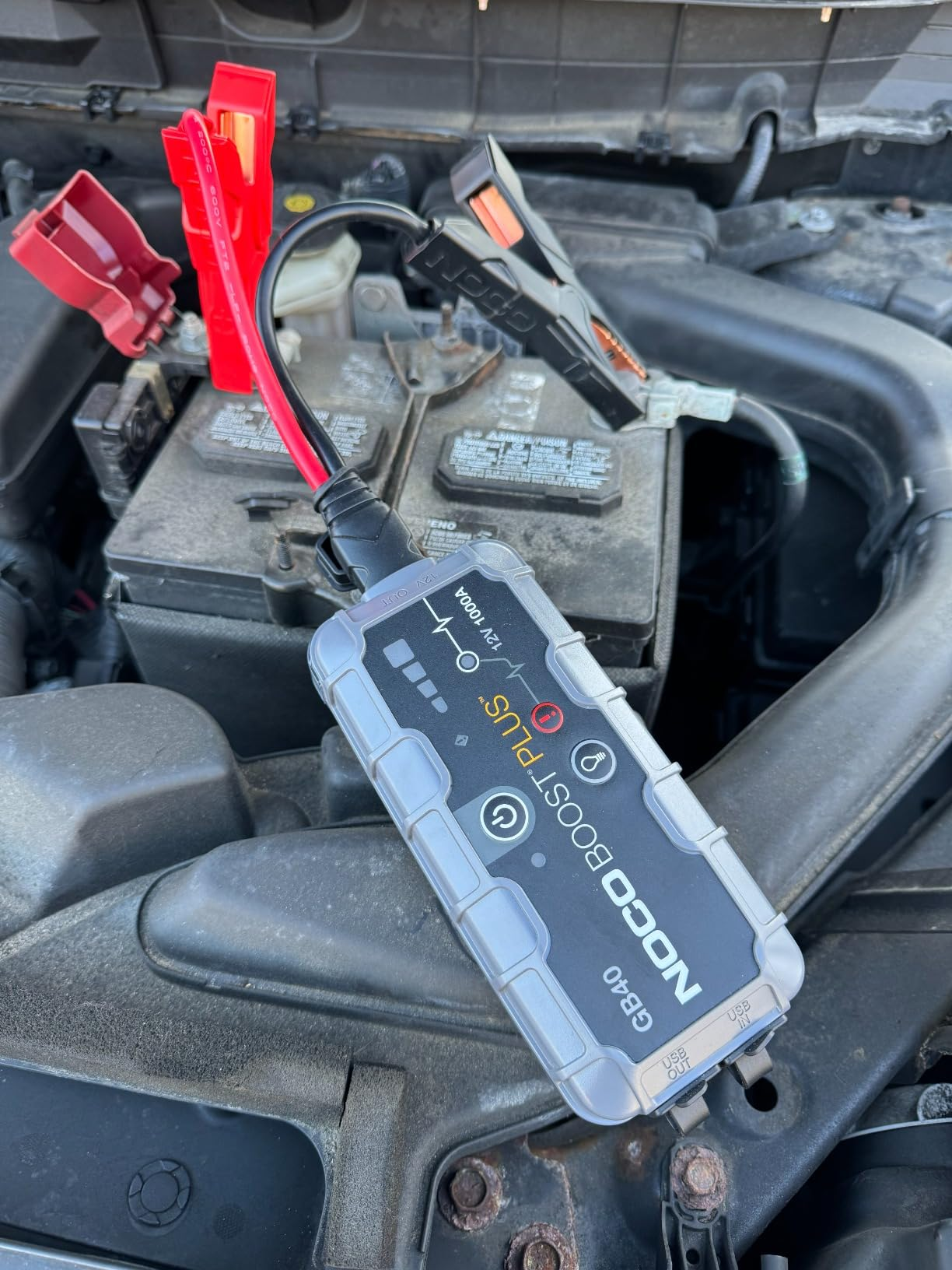 Portable leap  starter connected to a car   battery, showing an interface with indicators and controls