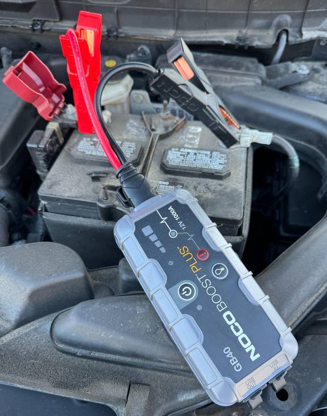 Portable leap starter connected to a car battery, showing an interface with indicators and controls