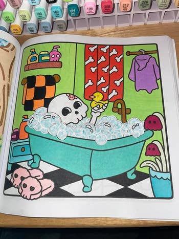 Cartoon skull in a bathtub with duck and bubbles, surrounded by quirky skull-themed bathroom decor. Coloring markers shown above