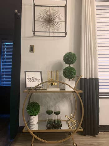 two-tiered bar cart with circle frame in gold holding decor in a reviewer's home