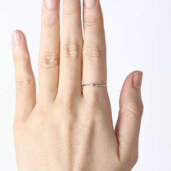 a model wearing the very thin band ring with a tiny stone in the middle