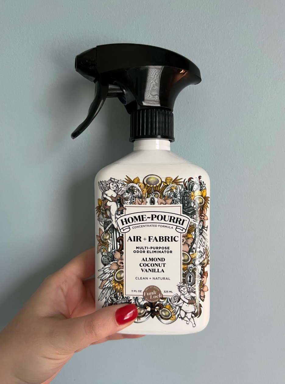 BuzzFeed editor Heather Braga holding up container of Home-Pourri air and fabric odor eliminator in almond coconut vanilla scent