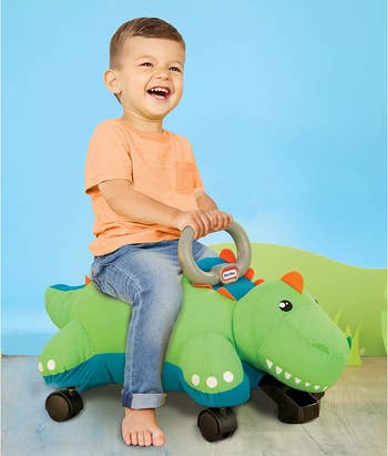 Child model riding atop green dinosaur racer