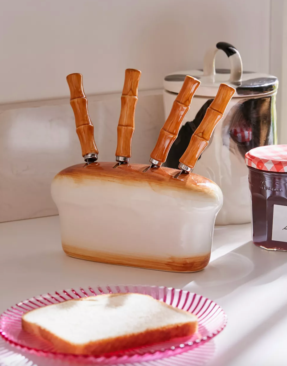 bread-shaped knife storage with four knives with brown handles sticking out of it