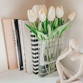 The clear vase on a table with white tulips