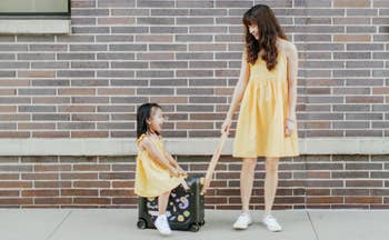 child model being pulled by adult model on suitcase