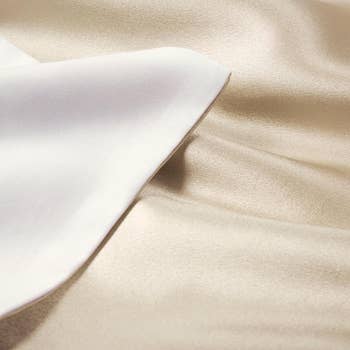 Close-up of smooth satin and cotton fabric layers, showcasing the contrasting textures for a luxury bedding article