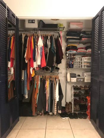 closet organization system with various rods and shelves and neatly-organized clothes, shoes, and accessories in double-door closet