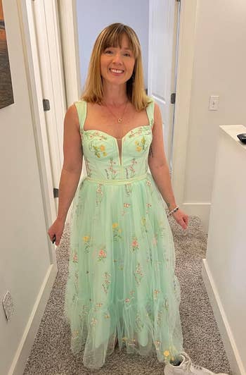 reviewer in a light green floral dress with a tulle overlay