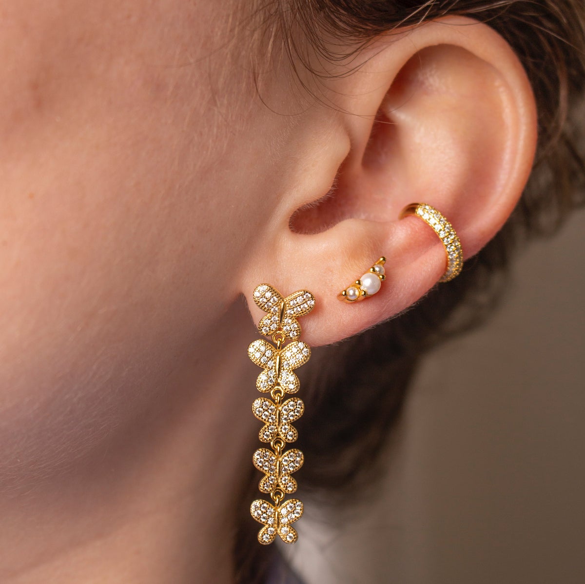 Image of model wearing gold butterfly drop earrings