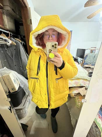 A person in a yellow, cozy hooded parka jacket