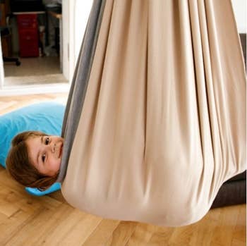 Child smiling while curled up inside the hanging fabric chair