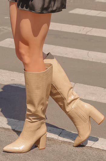 a model wearing the knee-high boots in light nude croc