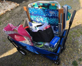 reviewer showing the blue wagon filled with assorted chairs and things needed to bring to the beach