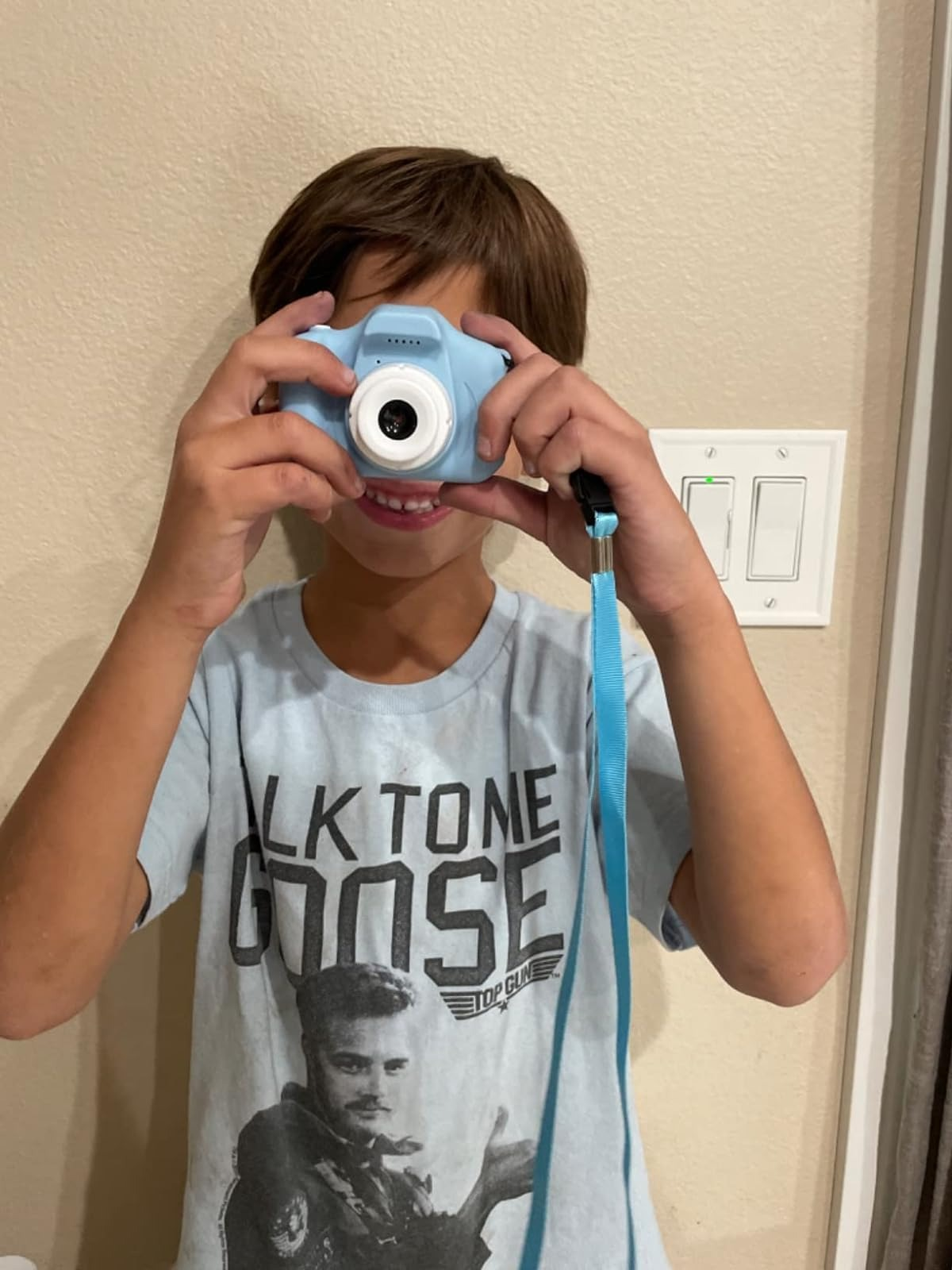 A kid  utilizing a tiny  bluish  camera