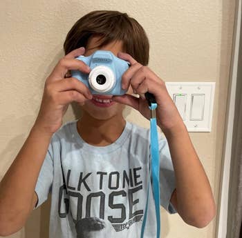 A kid utilizing a tiny bluish camera