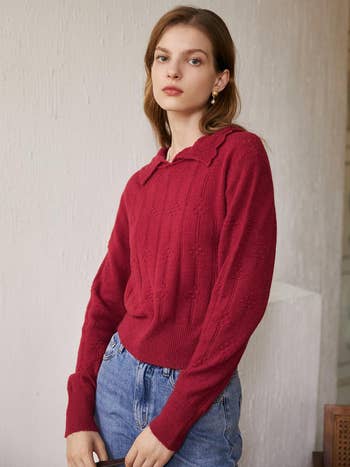 a model wearing a red knit polo sweater with blue jeans