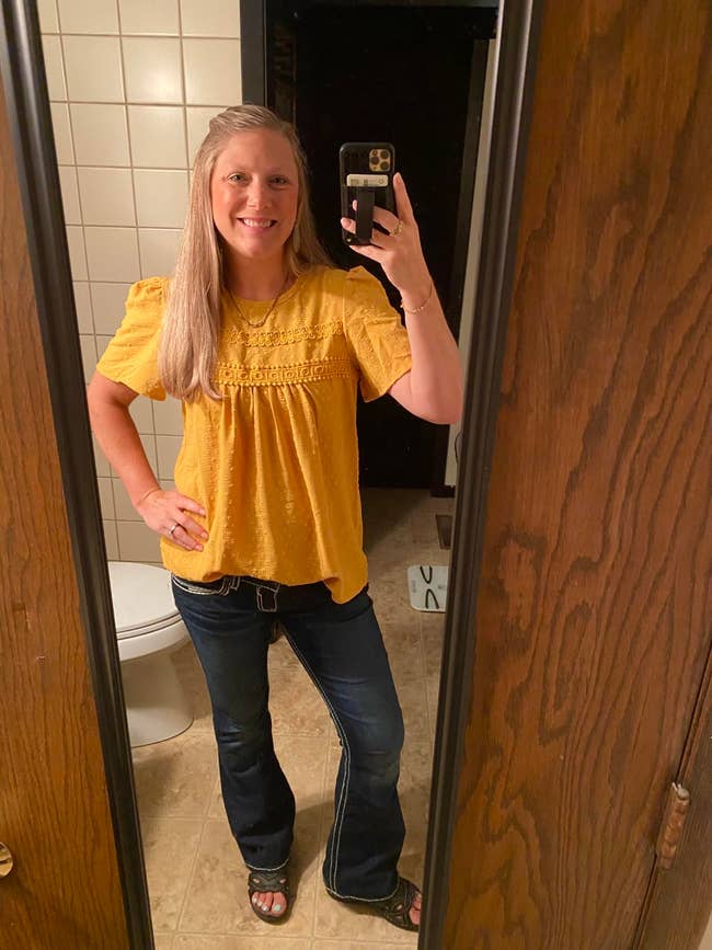Person taking a reflector  selfie successful  a bathroom, wearing a patterned blouse and jeans, showcasing casual benignant   for a buying  article