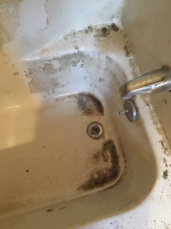 reviewer's dirty tub interior with dirt stains near the drain and walls
