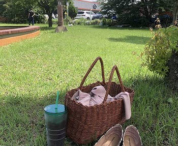 Reviewer's snake-print flats sitting outside in grass next to a drink and a bag