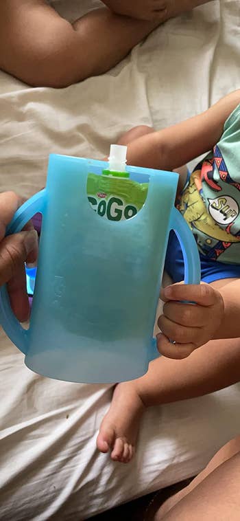 a reviewer photo of child's hand grabbing the holder with a food pouch inside