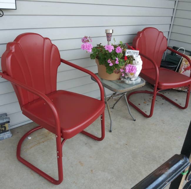 two of the tulip shaped chairs in red on a porch 