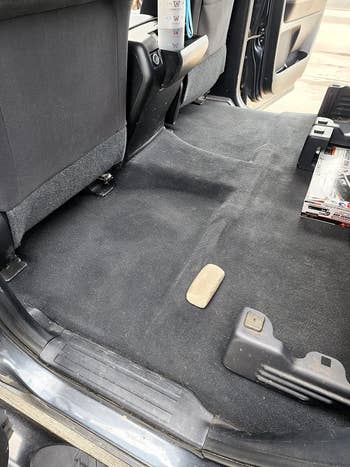 Car interior with disposable   backmost  spot   floor, showing cleanable  carpet, portion  of the conveyance  level  mat, and an automotive merchandise  container  connected  the side