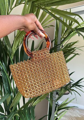 reviewer holding beaded bag showing circular tortoiseshell handle