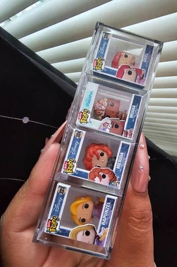 hand holding the four fingertip-sized figures in their boxes including surprise Ariel pop