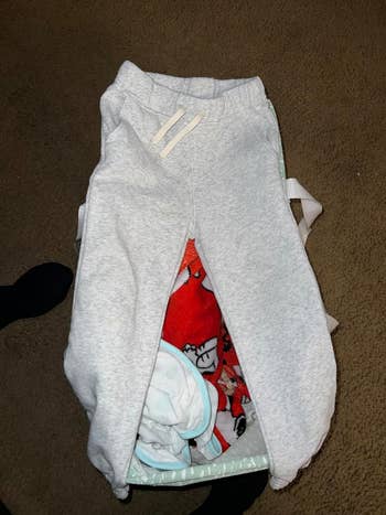 Gray sweatpants layered over patterned leggings with a character graphic, suggesting a comfortable, casual style